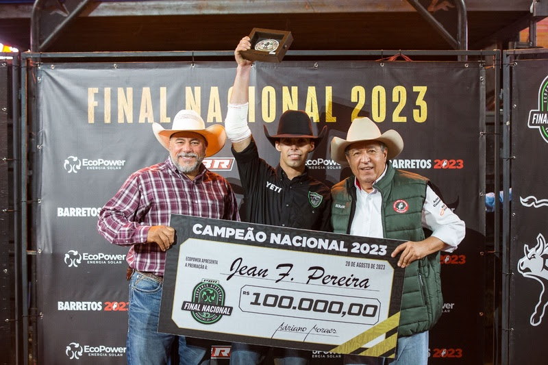 O competidor Jean Pereira levanta fivela de campeão nacional da PBR, ao lado do tricampeão mundial Adriano Moraes e do presidente da Festa do Peão de Barretos, Hussein Gemha Júnior - Crédito: Alberto Gonzaga