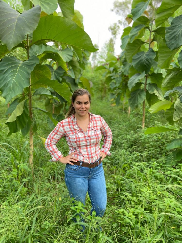 Ana Clara Gatto junto a plantação de árvores de teca